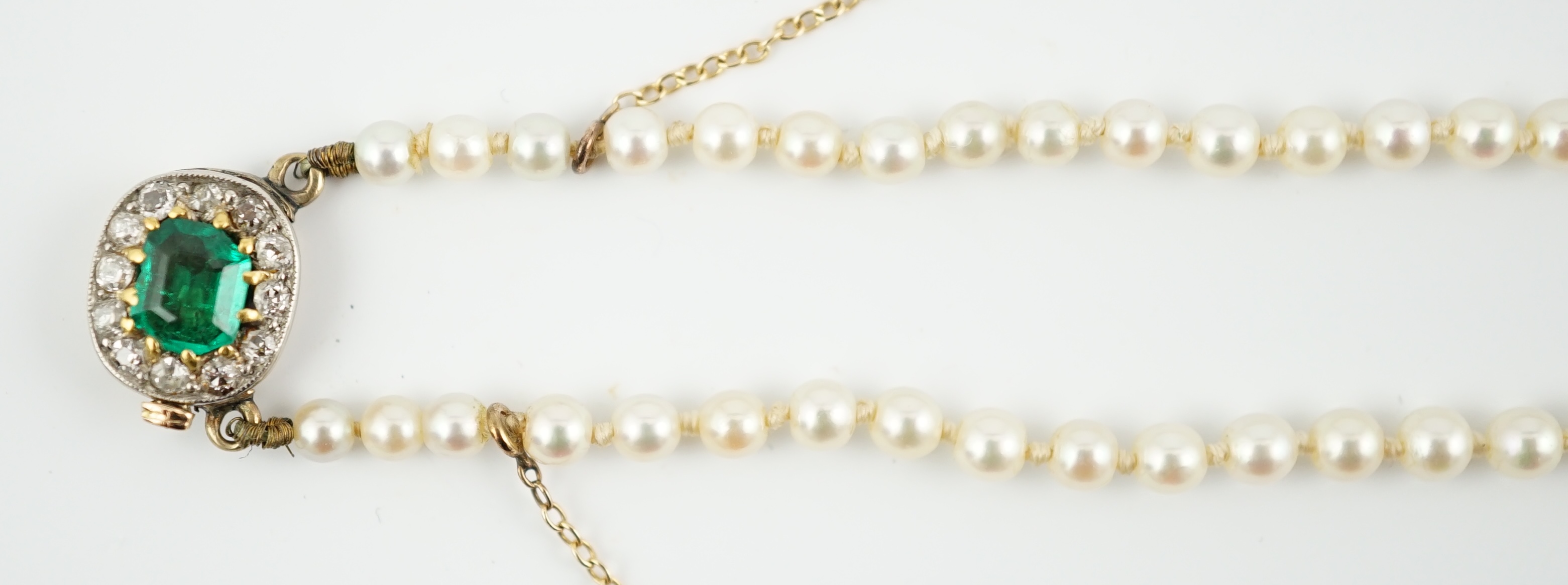 A single strand graduated cultured pearl necklace, with emerald and diamond cluster set gold clasp